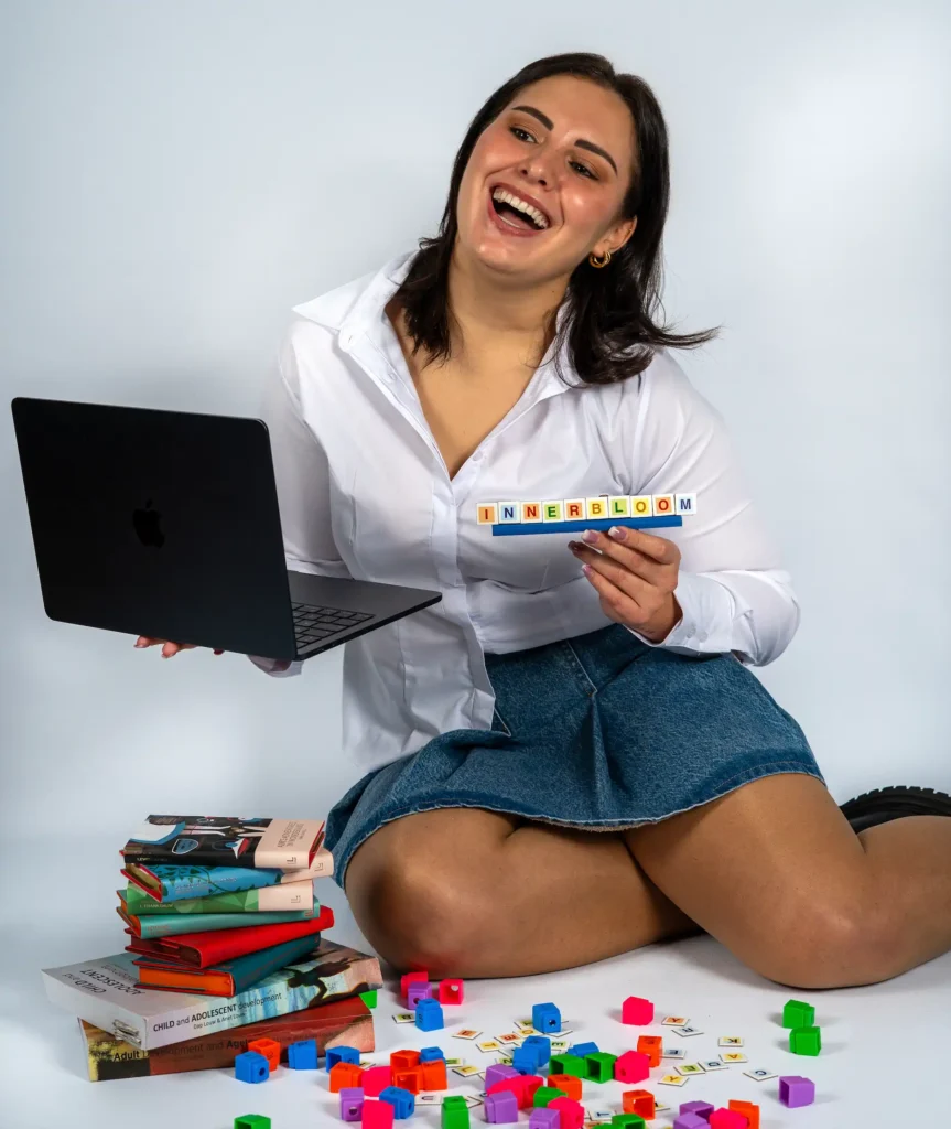 Innerbloom founder laughing while holding a laptop and INNERBLOOM letter tiles, offering online and personal tutoring