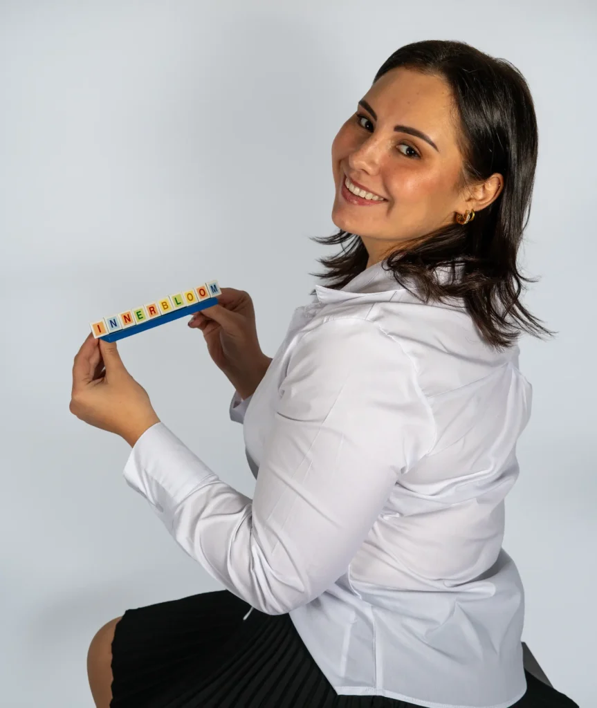 Innerbloom Tutoring founder smiling and holding INNERBLOOM letter tiles
